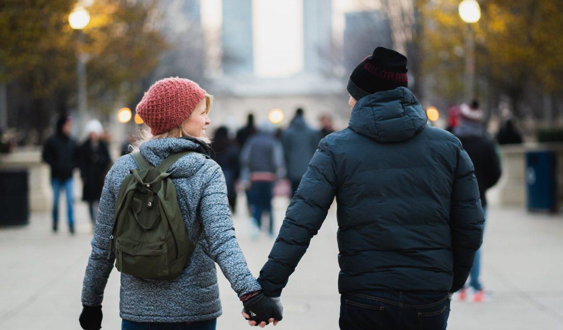 man and woman holding hands while walking at park